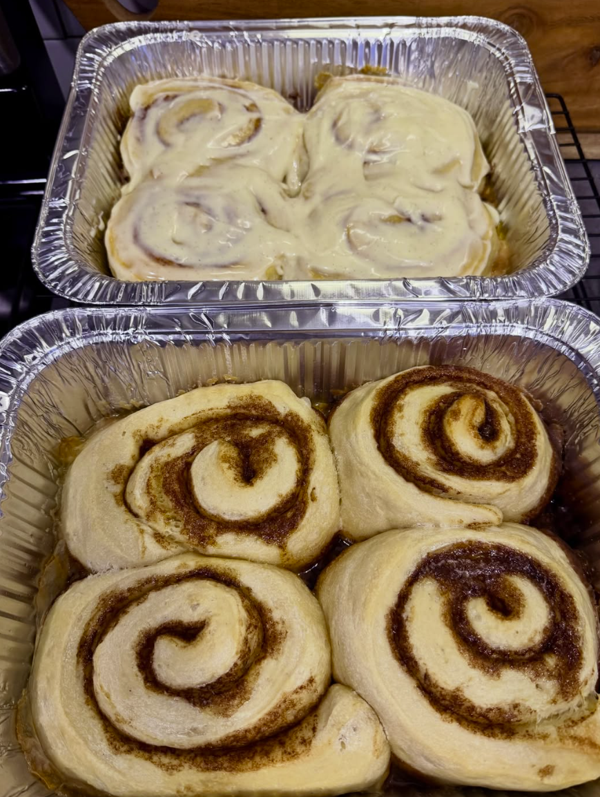 Glazed cinnamon rolls with visible swirls stacked on a plate